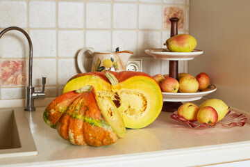 Beautiful large pumpkin with large seeds and red apples on a fruit stand on a table in the kitchen