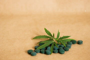 green leaf or cannabis leaves and pills on craft white background