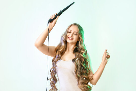 Beautiful Young Woman With Curling Iron For Hair Against Color Background