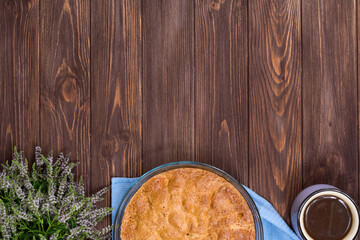 Fresh baked pie on a dark wooden surface with a cup of tea and linden blossom. Place for an inscription. View from above.