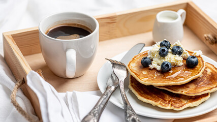 Sunday morning. Delicious breakfast of pancakes, berries and coffee on a wooden tray.