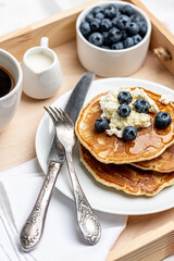 
Tasty breakfast. Pancakes with cottage cheese and honey, fresh berries and a cup of hot black coffee on a wooden tray.
