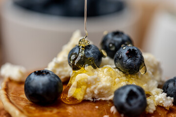 
Delicious pancakes with blueberries, cottage cheese and honey for breakfast. Close-up.