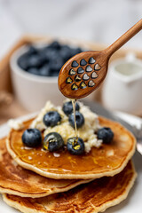 
Healthy food. Freshly cooked pancakes with blueberries, honey and cottage cheese for breakfast.