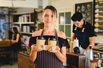 Female barista giving coffee in cardboard cups,concept: environmental protection, nature conservation, recycle.