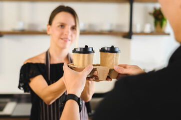 Female barista giving coffee in cardboard cups,concept: environmental protection, nature conservation, recycle.