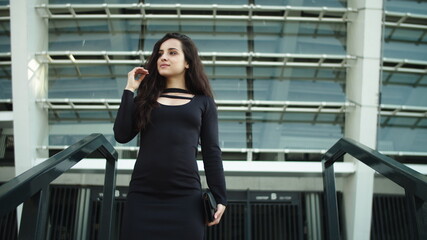Fototapeta premium Portrait woman touching hair outside. Business woman smiling on stairs outdoors
