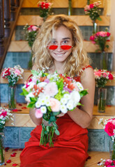 Portrait of a blonde girl in red glasses with a bouquet of flowers