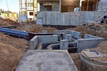 Naklejka premium Laying heating pipes in a trench at construction site. Install underground storm systems of water main and sanitary sewer. Cold and hot water, heating and heating system of apartments in the house