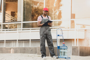 African-American delivery man with bottle of water outdoors