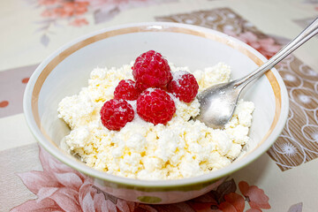 Cottage cheese in a plate decorated with fresh raspberries and sprinkled with sugar. Dietary and healthy food.