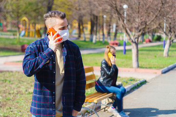 a guy and a girl are sitting on a bench at a distance talking to each other on the phone