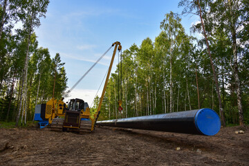 Fototapeta na wymiar Natural gas pipeline construction work in forest area. Crawler crane with side boom Pipelayer Installation of gas and crude oil pipes in ground. Construct of the gas pipes to new LNG plant