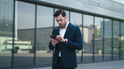 Closeup businessman reading bad news at street. Businessman using smartphone
