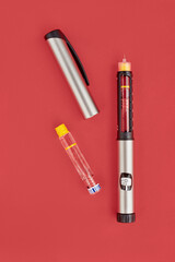 Insulin Pen on red background, close-up, flat lay. Diabetes control concept