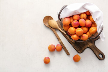 Basket with tasty ripe apricots on light background
