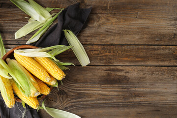 Bowl with fresh corn cobs on table