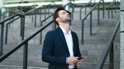 Fototapeta premium Closeup man typing on phone at city. Business man looking away at street