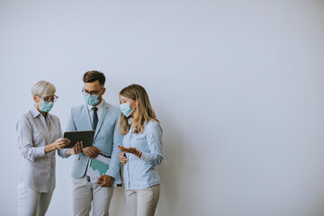 Business partners standing and looking at business results in office while wearing face masks sa an virus protection