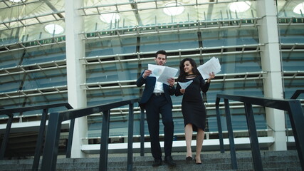 Business man and woman going downstairs. Man and woman throwing documents