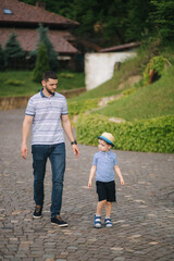 Fototapeta premium Father walking with sun outdoors. Happy family. Boy in straw hat