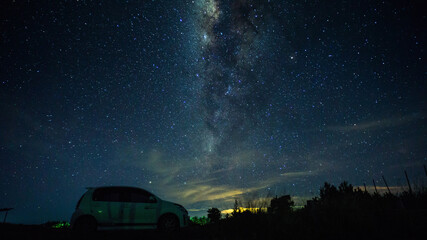 Milky-way and stars Galaxy across the night sky with silhouette of car. Image contains noise due to...