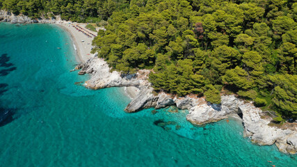 Aerial drone photo of secluded rocky cove near turquoise pebble paradise beach of Kastani covered with pine trees, Skopelos island, Sporades, Greece