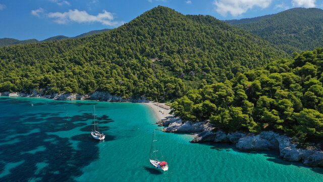 Aerial drone photo of secluded rocky cove near turquoise pebble paradise beach of Kastani covered with pine trees, Skopelos island, Sporades, Greece