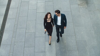 Top view couple walking together at sidewalk. Business partners talking outside