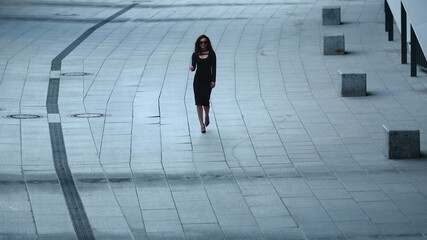 Woman walking in slow motion at sidewalk. Woman taking off sunglasses at street