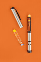 Insulin Pen on orange background, close-up, flat lay. Diabetes control concept