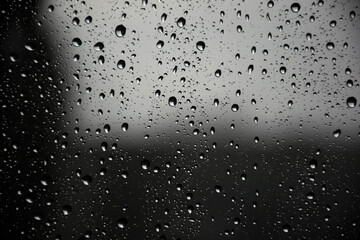 Raindrops on the window pane slowly flowing down