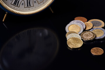 clock and coins on black glass
