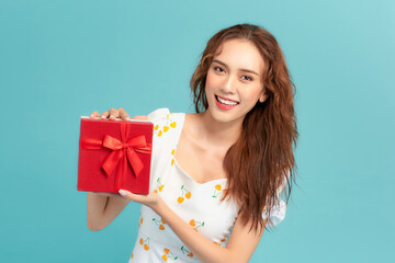 Happy smiling girl in dress holding present box and  over blue background