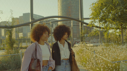 two mixed race black woman with huge afro walking in the park Portrait of talking mixed race women walking