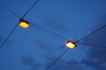 Dwie świecące latarni na kablach wieczorem na tle nieba we Wrocławiu, Polska