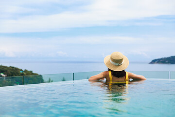 Fototapeta na wymiar Asian travel bikini woman relax in infinity pool on phuket beach Thailand