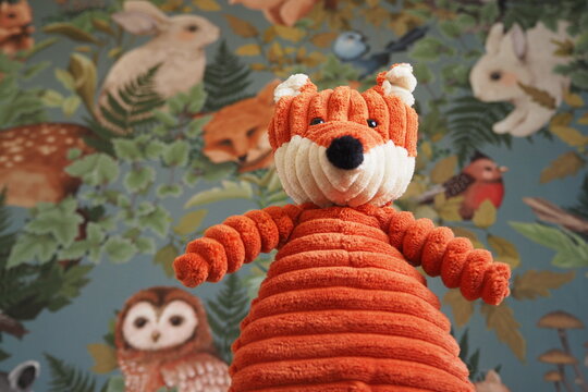 Zabawka dla dzieci rudy lis na tle kolorowej tapety