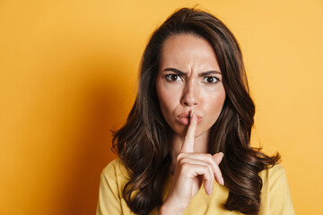 Fototapeta premium Image of angry brunette woman showing silence gesture