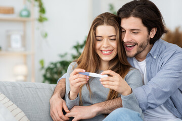 Closeup of happy hugging couple holding positive pregnancy test © Prostock-studio