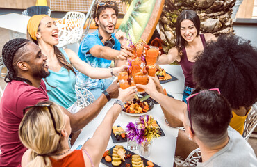 Diverse people friends hanging out toasting and drinking cocktails outdoor.