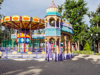 Bright colorful children's carousel without people in the park in the evening