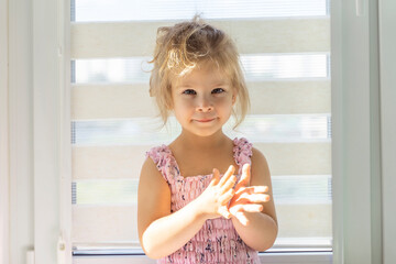 portrait of a beautiful little girl on the background of a window on a sunny day. sun glare