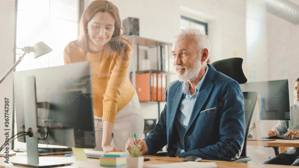 Poster Handsome Middle Aged Creative Engineer Sitting at the Desk working on Desktop Computer Has Discussion with Beautiful Female Project Manager. Office with Friendly Colleagues Chatting, Finding Solutions
