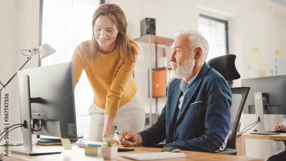 Poster Handsome Middle Aged Creative Engineer Sitting at the Desk working on Desktop Computer Has Discussion with Beautiful Female Project Manager. Office with Friendly Colleagues Chatting, Finding Solutions