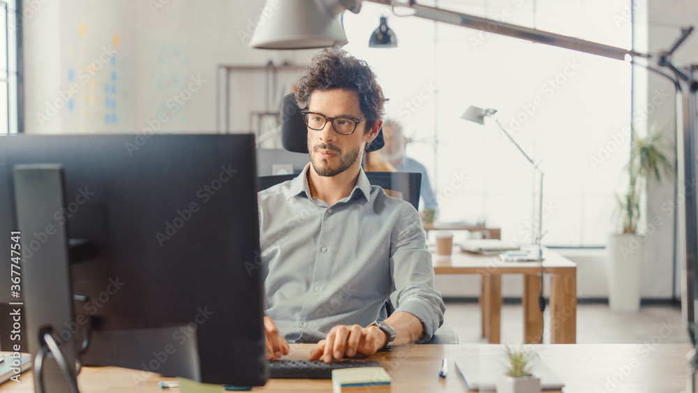 Poster handsome and smart hispanic office employee sitting at his desk works on a desktop computer. in the 