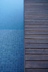 Blue swimming pool with wooden deck       