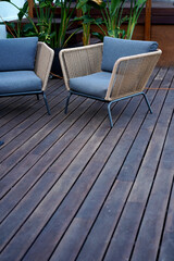 Natural wooden floor terrace with nice sofa and chairs with grey textile materials.       