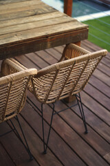 Wooden rustic table on a deck terrace with natural wood floor.Arm chairs with metal legs.