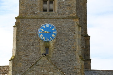 A traditional clock with a blue face and Roman numerals in a Church tower in England.